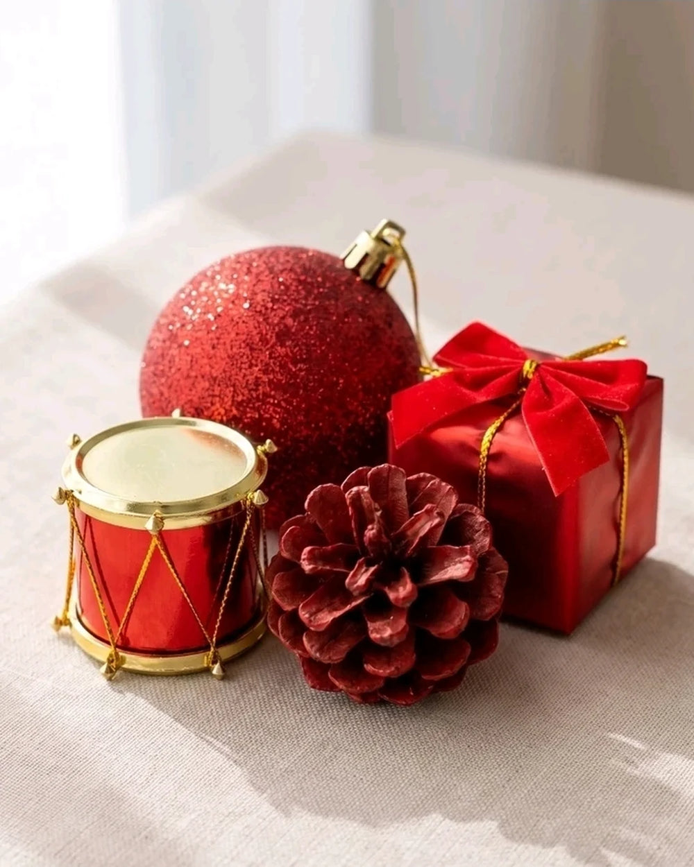 Tambor com aro dourado, bolinha com glitter, pinha vermelha e presente com laço