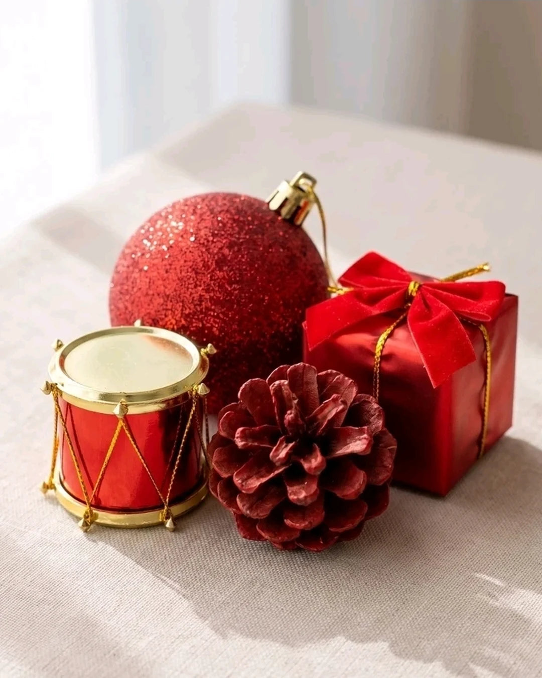 Tambor com aro dourado, bolinha com glitter, pinha vermelha e presente com laço