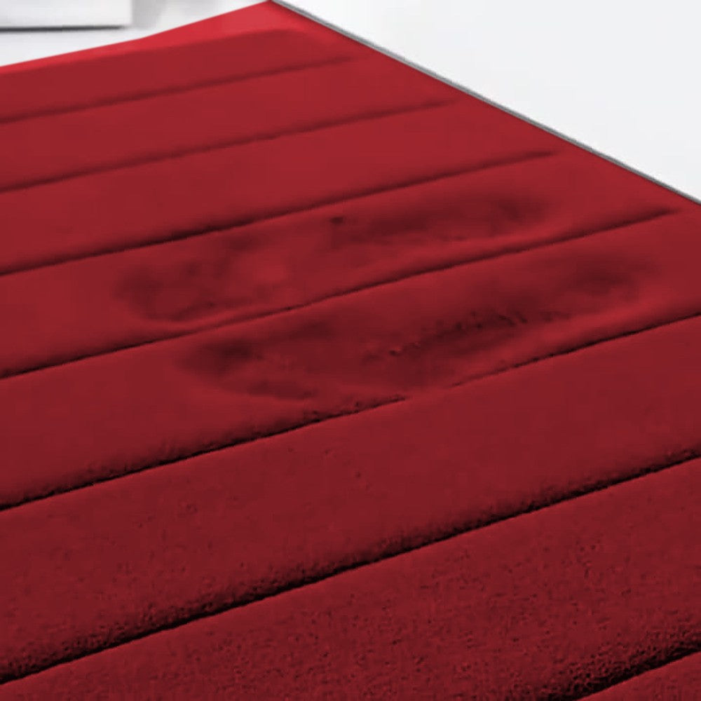 Tapete de banheiro vermelho absorvendo a água das pegadas